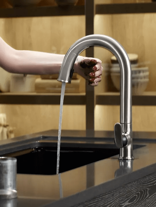 Person using touchless Kohler faucet in kitchen