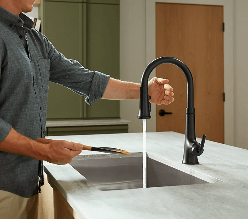 Man holding kitchen utensil under Kohler touchless faucet